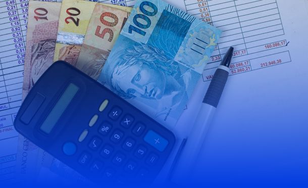 calculadora, notas físicas de dinheiro e caneta sobre uma mesa